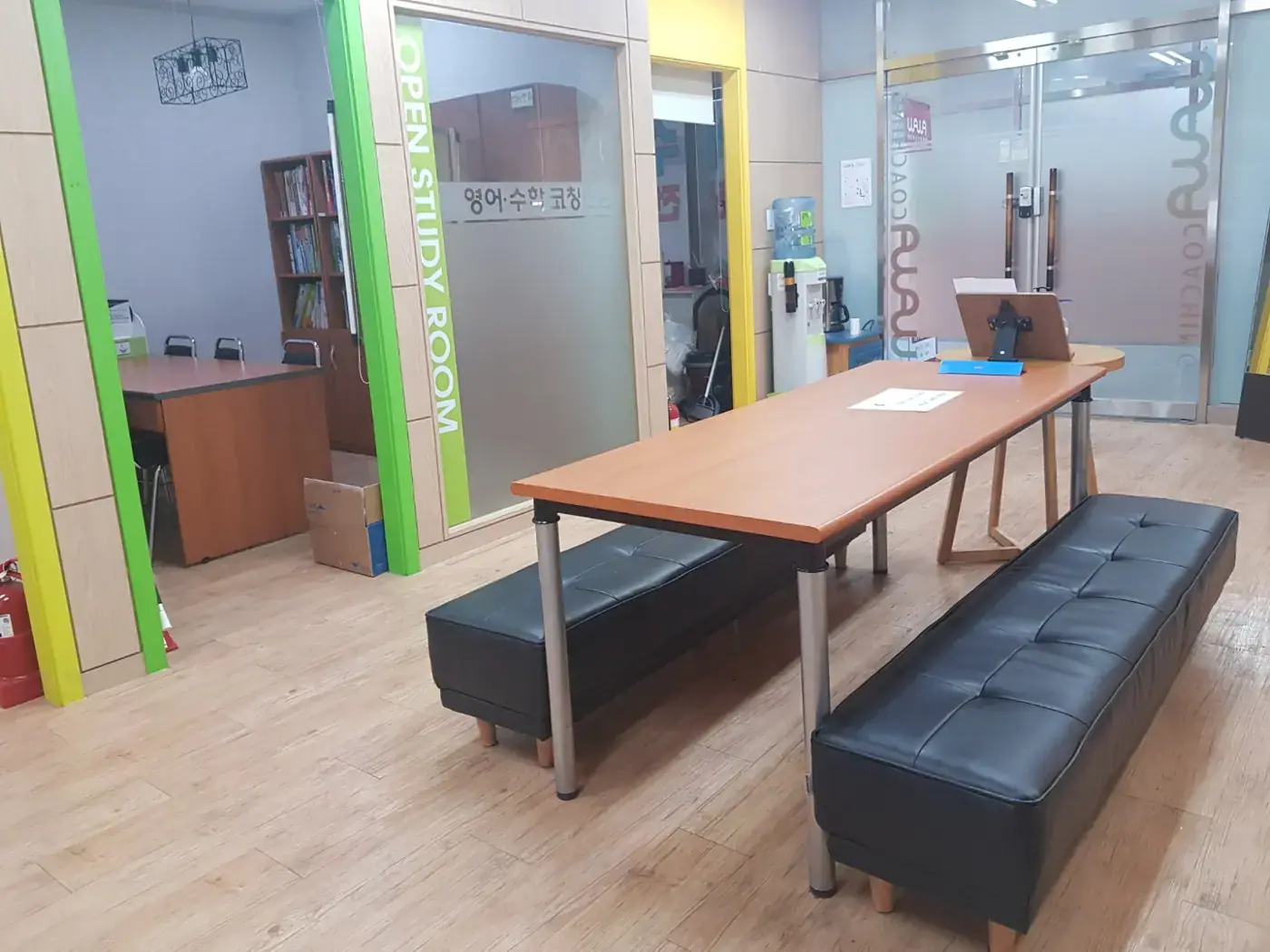 OPEN STUDY ROOM 글자가 붙은 유리벽 앞에 긴 원목 테이블과 검은 벤치가 놓인 은평점 오픈 학습 공간