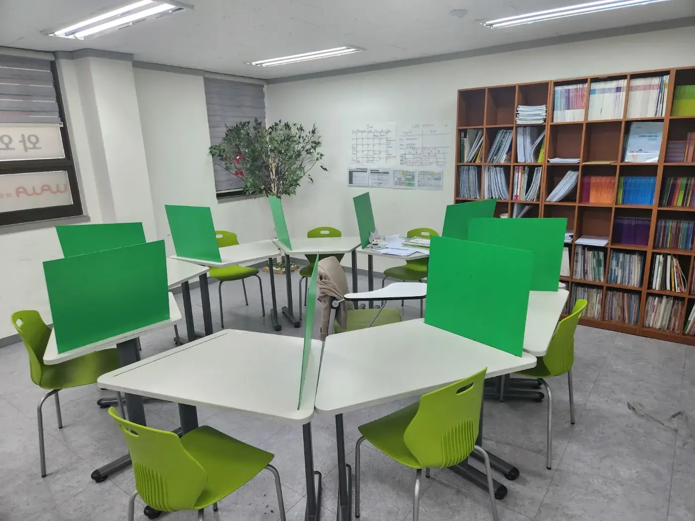 원목 교재 책장과 화분 옆으로 육각형 칸막이 책상이 모인 철산점 학습실