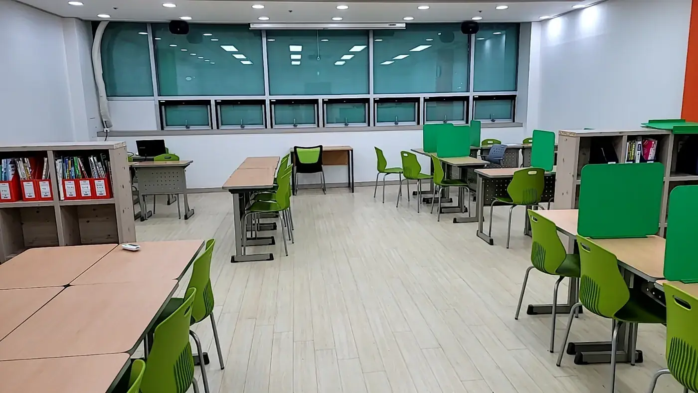 넓은 창 아래 연두색 의자와 책장이 놓인 퇴계원점 학습실