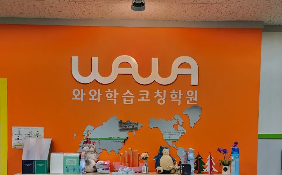 주황색 벽에 와와학습코칭학원 로고와 세계지도 장식이 걸린 이매점 안내 공간