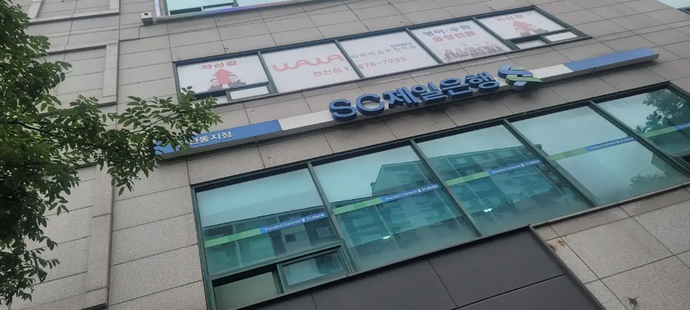 은행 위층 창문에 와와 로고와 천천점 안내가 붙어 있는 건물 외관