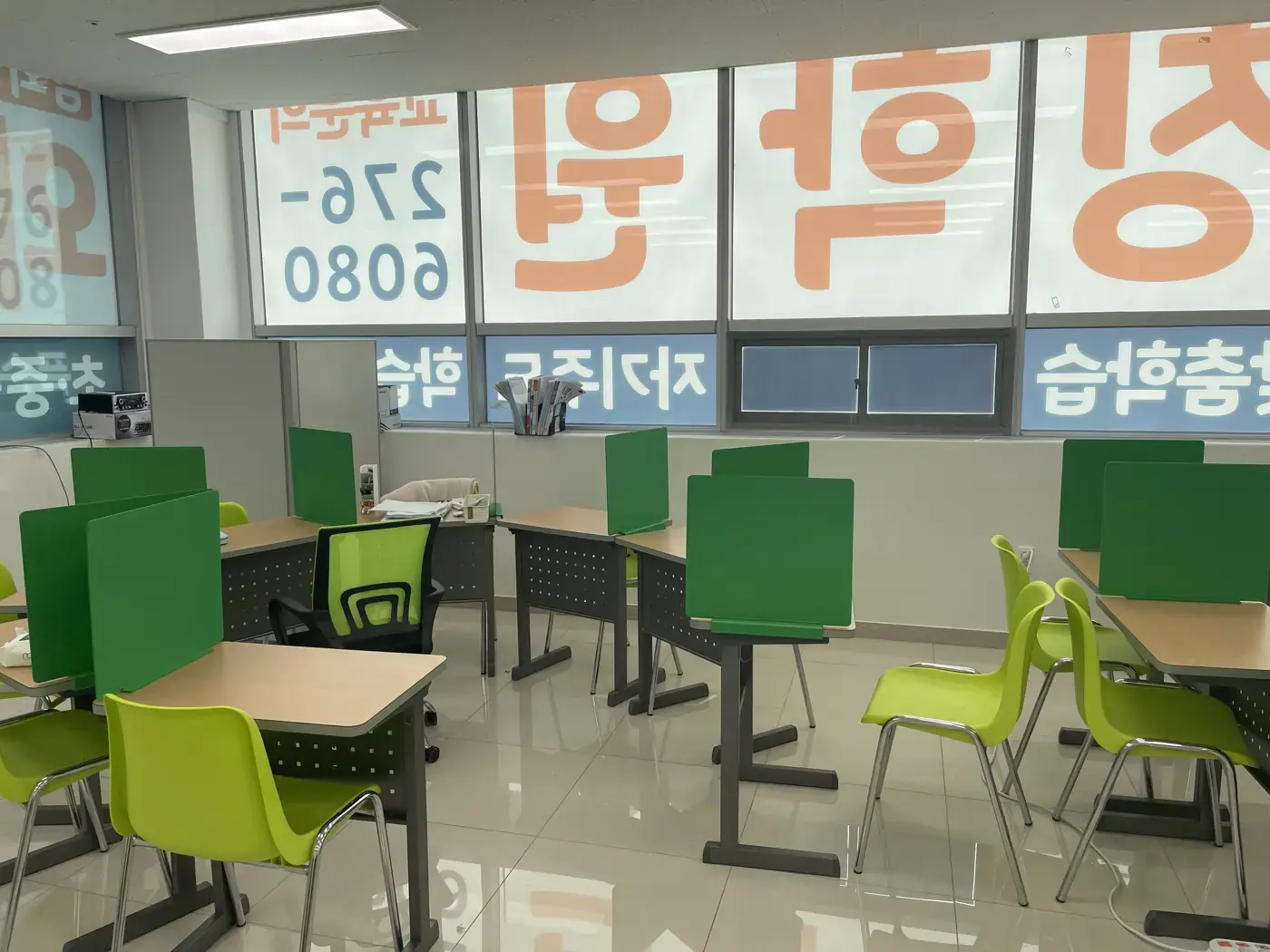 큰 창에 주황색 학원 이름 시트지가 붙어 있고 초록 칸막이 책상이 배치된 남외점 학습실
