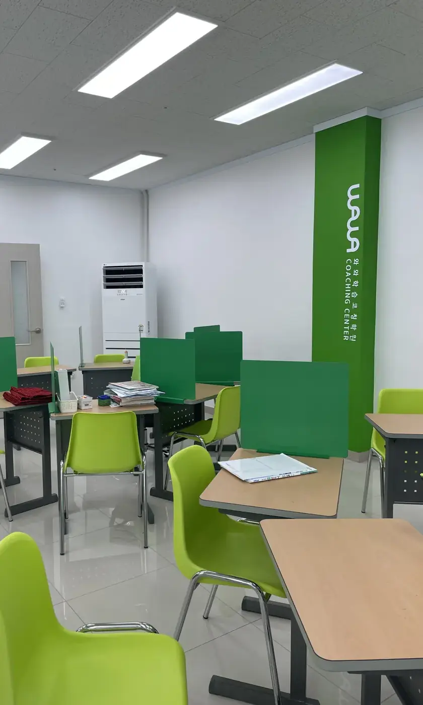 초록색 WAWA 기둥과 연두색 의자, 칸막이 책상이 놓인 남외점 자습 공간